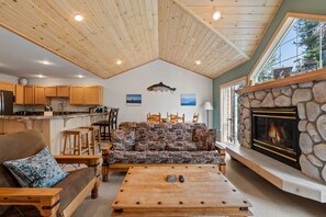 Ein gemütliches Wohnzimmer mit Kamin, Holzmöbeln und Blick ins Freie.