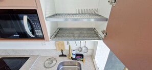 A kitchen with a microwave, a sink, and a stainless steel rack. - COCDV0103 - Edificio Alive (Salvador)