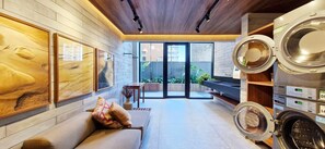 A modern laundry room with a sofa, artwork, and a view of the outside. - COCDV0103 - Edificio Alive (Salvador)