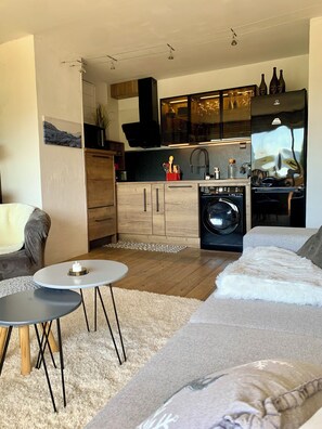 A modern living room with a grey sofa, a small round table, and a fluffy rug. - Charming 1-bedroom apartment in Megève, 10' walking of ski shuttle/village (Megève)