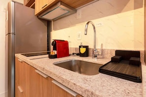 A kitchen with a stainless steel refrigerator, a built-in oven, a sink with a faucet, and a coffee maker. - Jardim Botânico Apt – Up to 3 Guests (Rio de Janeiro)