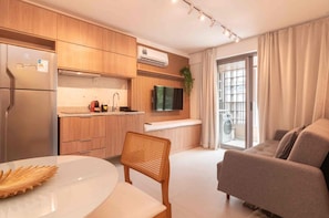 A modern kitchen with wooden cabinets, a built-in stove, and a flat-screen TV. - Jardim Botânico Apt – Up to 3 Guests (Rio de Janeiro)