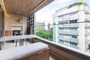 A modern apartment with a balcony, a washing machine, and a view of a cityscape. - Jardim Botânico Apt – Up to 3 Guests (Rio de Janeiro)