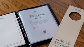 Een welkomstfolder, een sleutelkaart en een plant op een houten tafel.