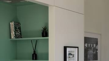 A kitchen with a green wall, a coffee machine, a plant, and a framed picture on the wall.