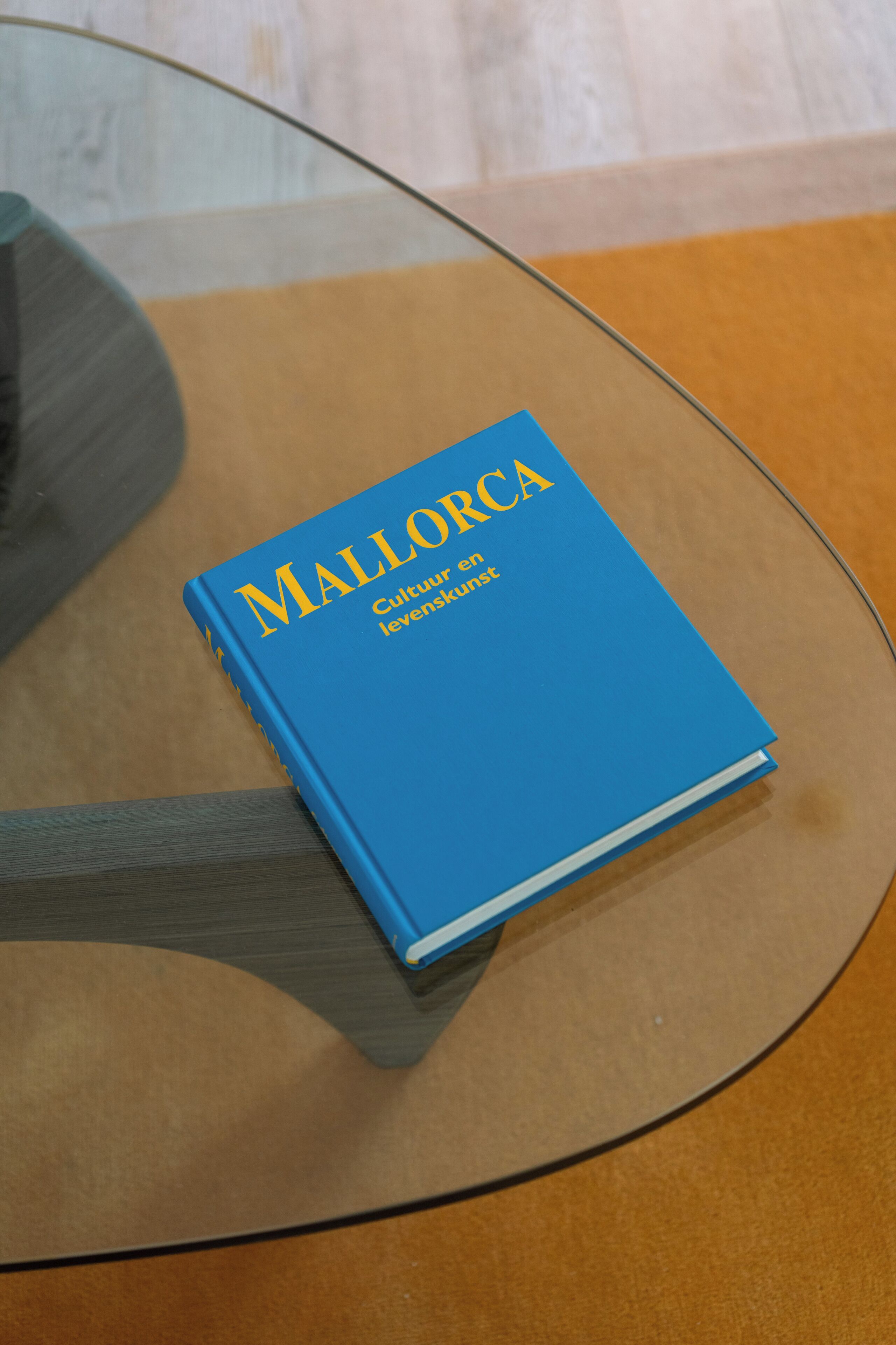 Un livre bleu intitulé « Majorque » est posé sur une table en verre.