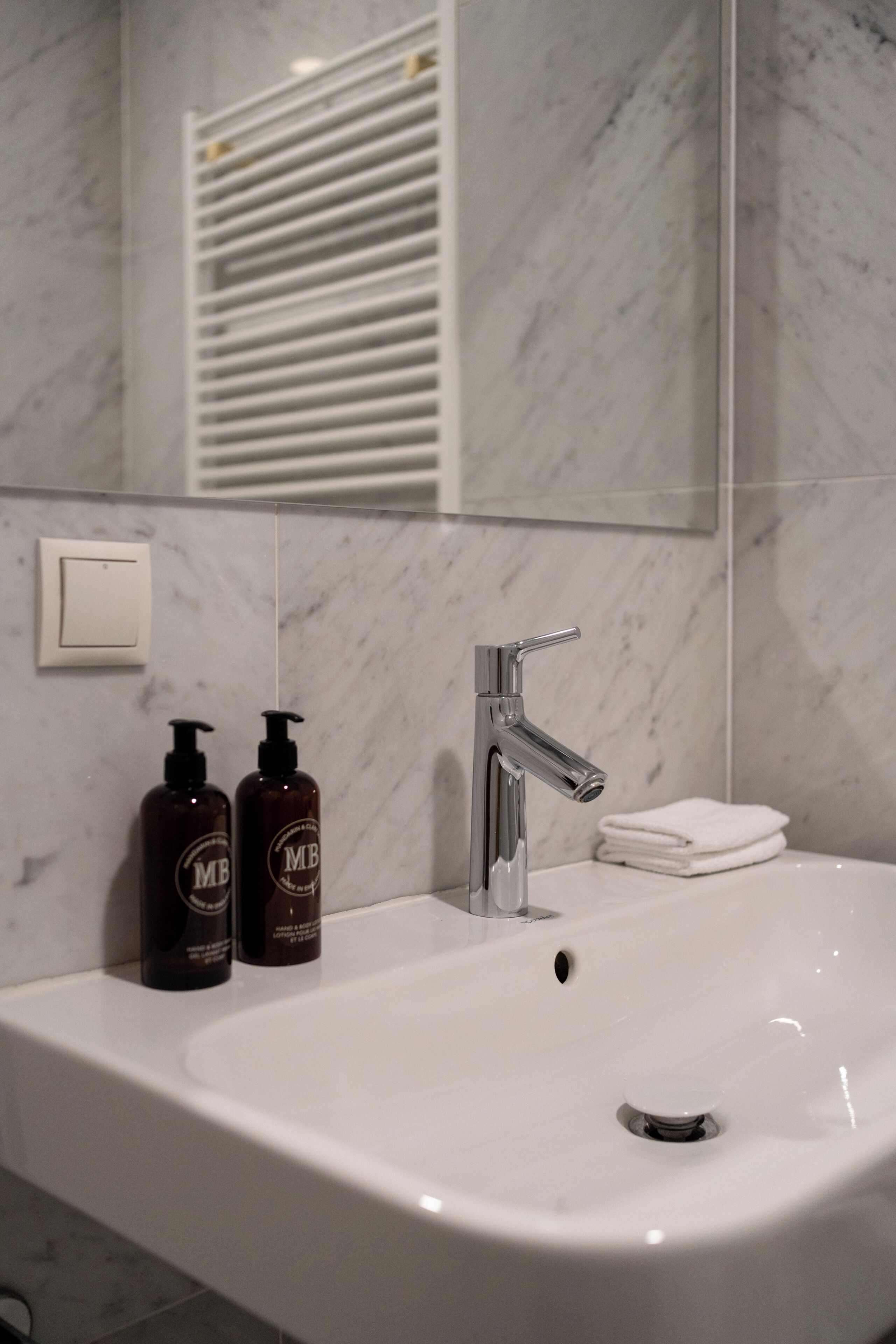 A bathroom with a white sink, a mirror, and two bottles of hand soap.