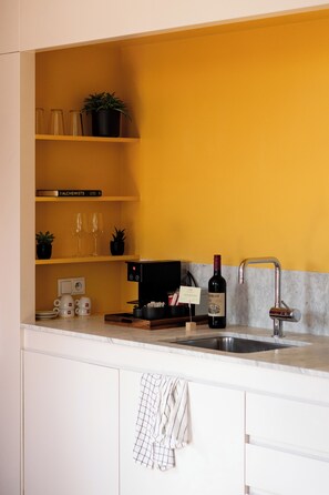 Uma cozinha com parede amarela, uma garrafa de vinho e uma máquina de café.