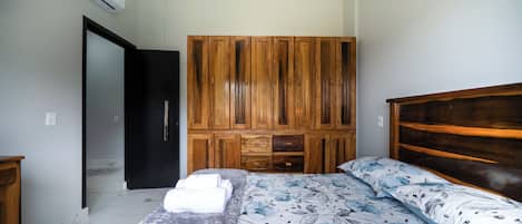 A bedroom with a bed, a wardrobe, and an air conditioning unit.