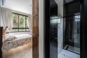 Un dormitorio con cama, ventana y vista a espacios verdes.