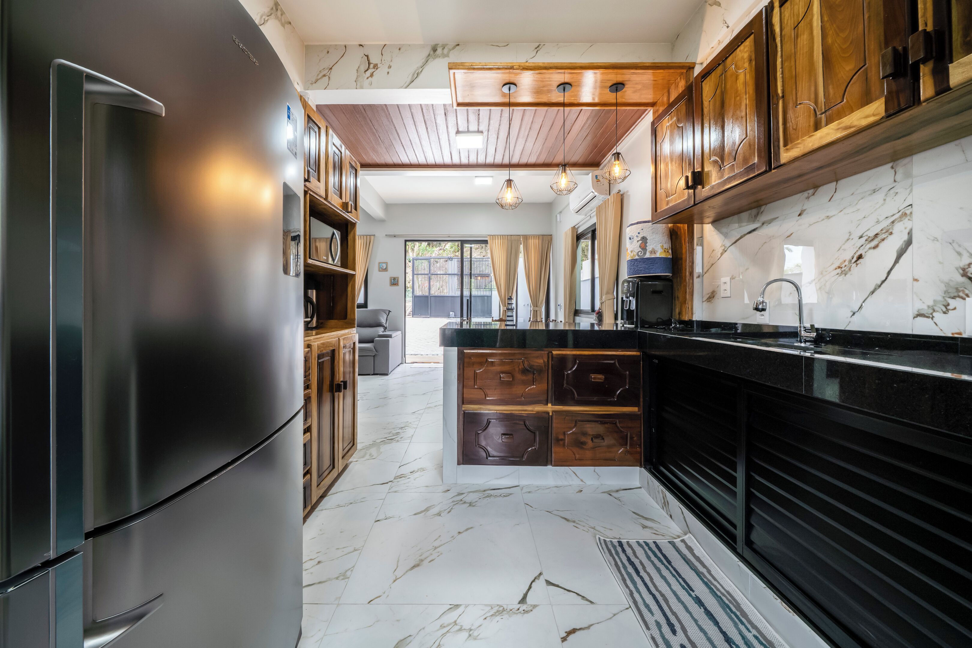 A modern kitchen with marble flooring, wooden cabinets, and a stainless steel refrigerator.