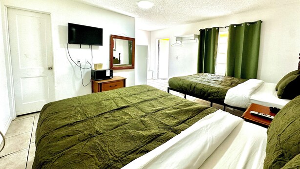 Habitación de hotel con dos camas, televisión, espejo y ventana con cortinas.