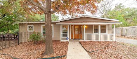 A single-story house with a front porch, a visible garage door, and a leaf-covered lawn.