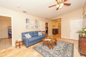 A living room with a blue sofa, a coffee table, and a patterned rug. - Medical Center / Sunset Hills Oasis - 78228 (San Antonio)