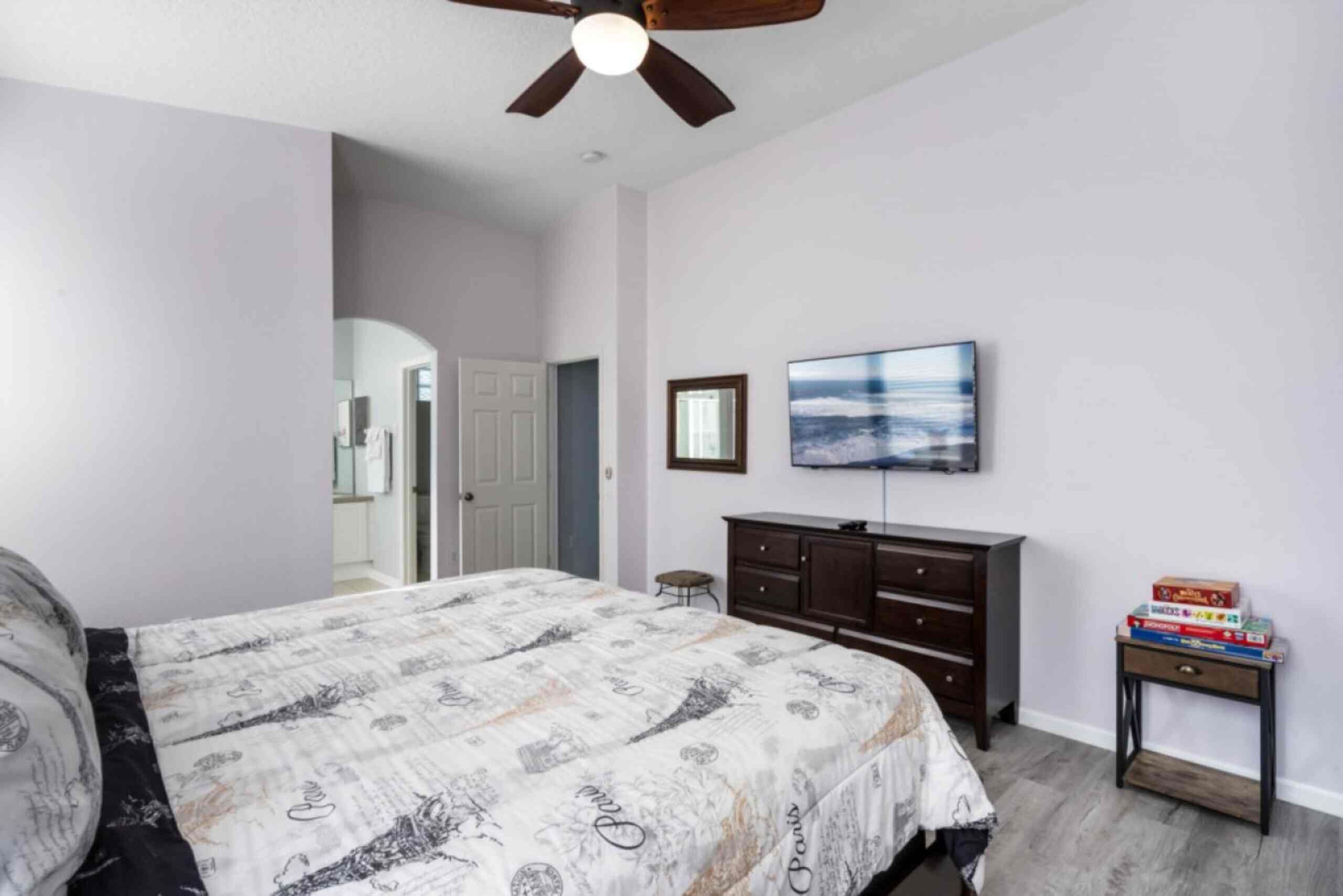 Une chambre à coucher avec un lit, une commode, une télévision et une petite table avec des livres.