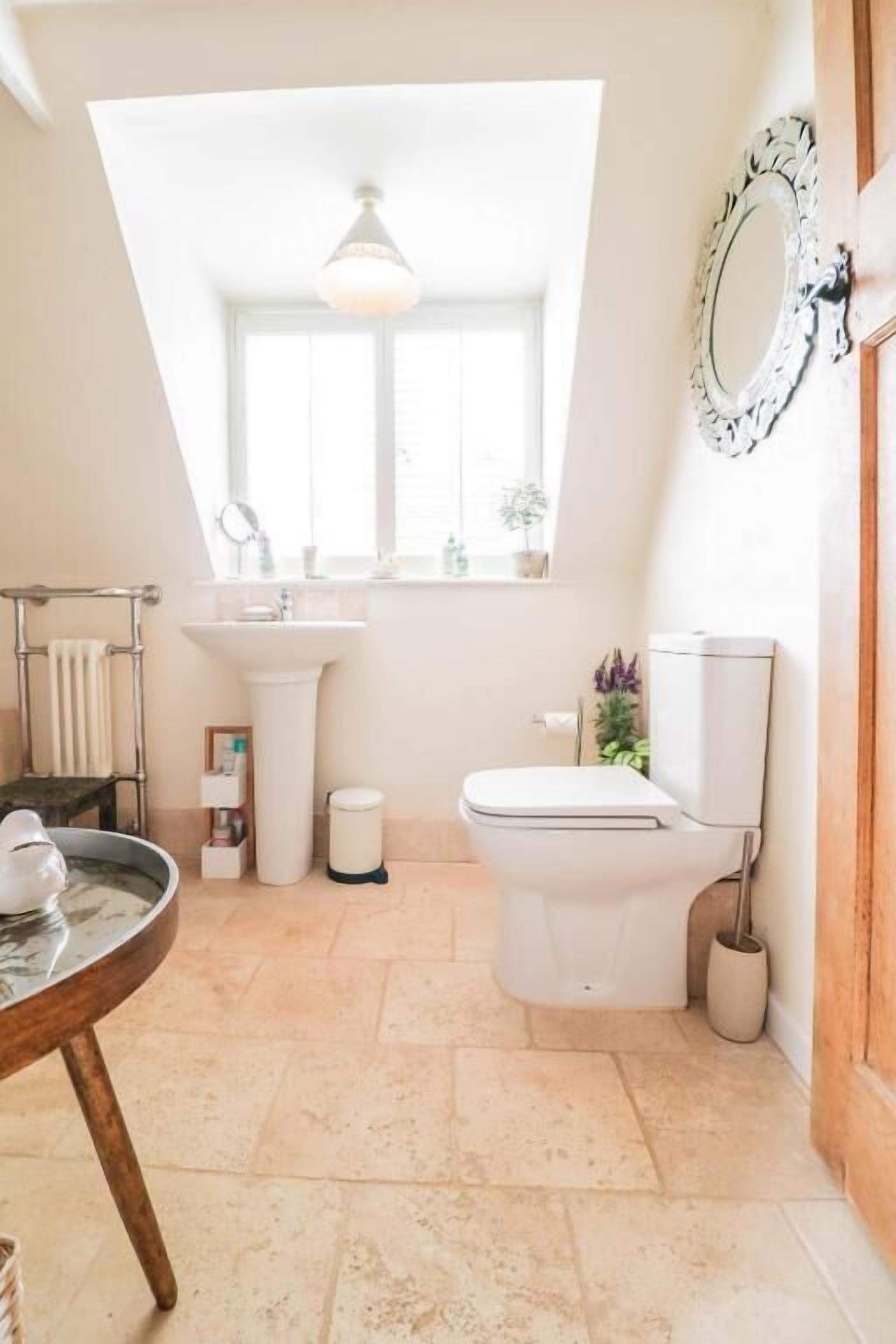 A bathroom with a window, a sink, a toilet, and a mirror.