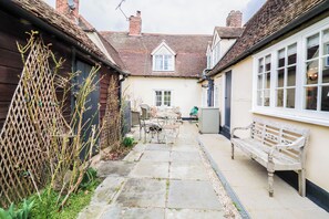 A narrow courtyard with a stone pathway, a wooden fence, and a bench. - Delightful Period Cottage 225 Oak Road (Rivenhall)