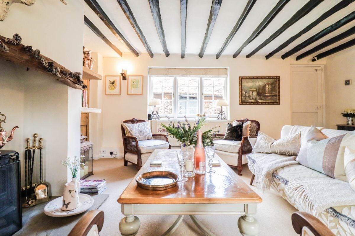 A cozy living room with a wooden coffee table, a fireplace, and a large window with white shutters.