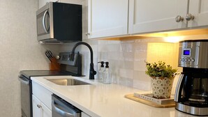 Eine moderne Küche mit Edelstahlgeräten, einer Mikrowelle, einer Kaffeemaschine und einem Blumentopf auf der Arbeitsplatte.