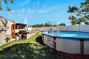 Ein Garten mit Swimmingpool, Grill und einer Leiter zum Pool.