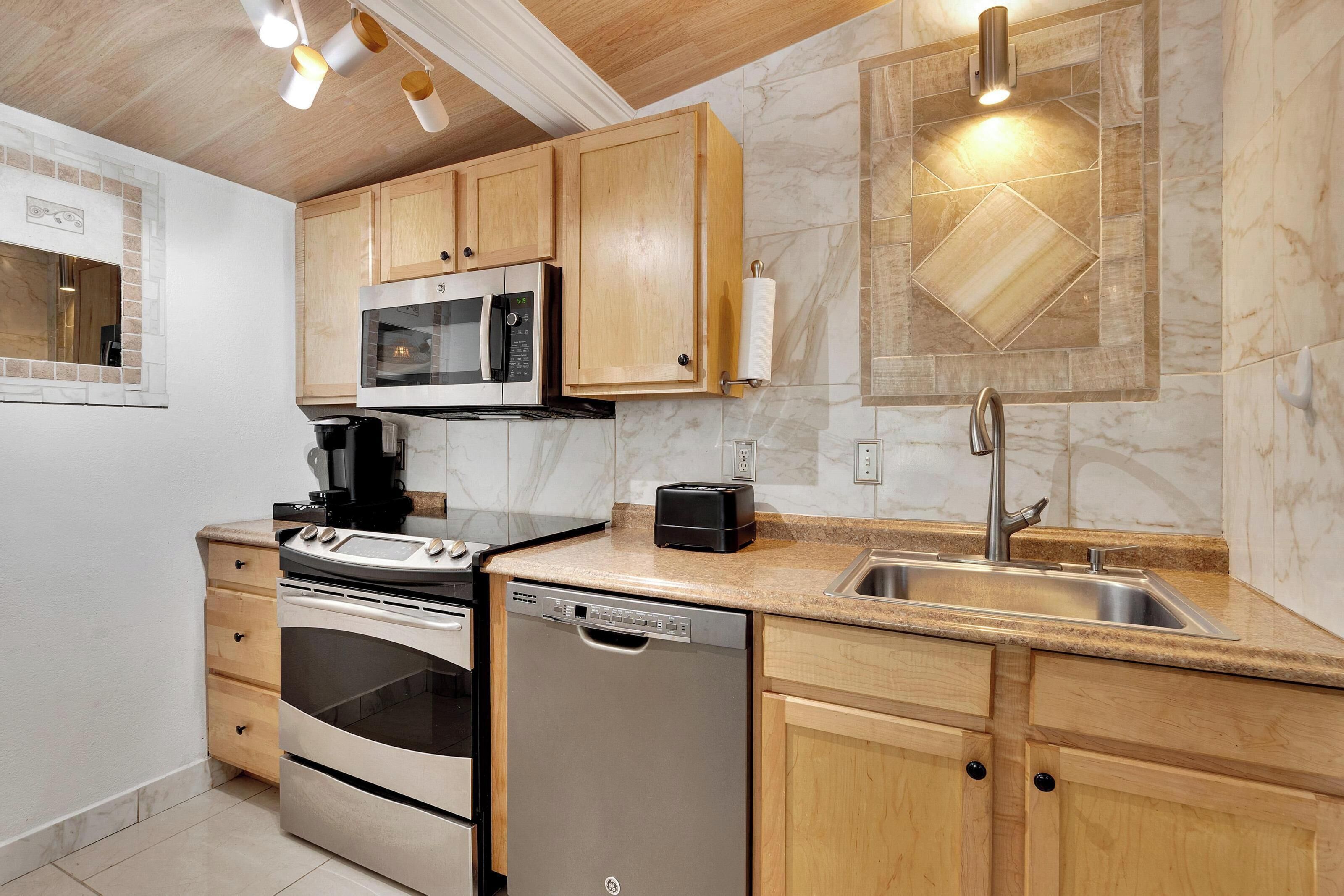 A modern kitchen with wooden cabinets, a built-in microwave, a stove, a dishwasher, and a sink.
