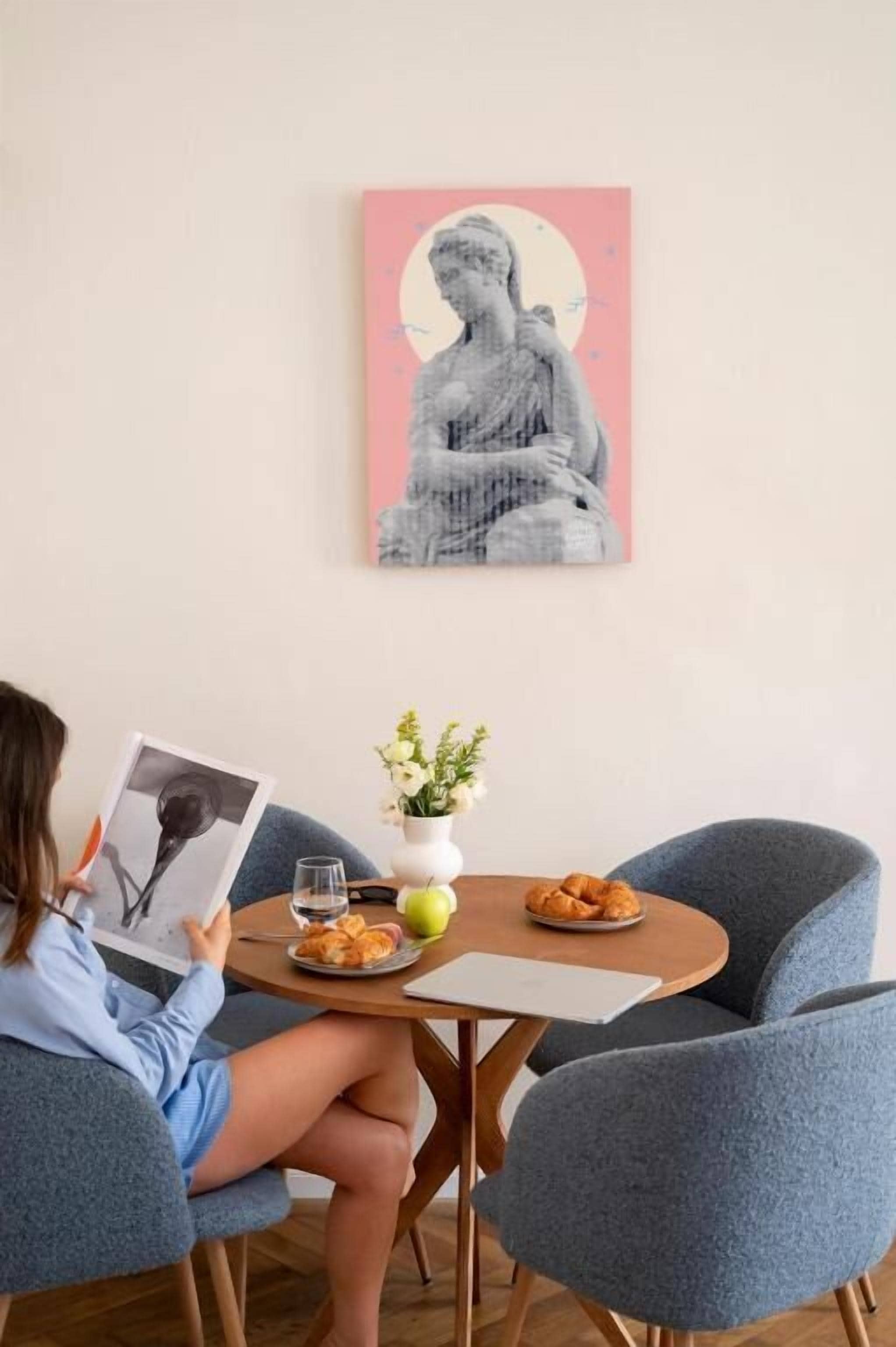 Une personne est assise à une table, devant un livre, avec une statue de Bouddha, des fleurs et de la nourriture.