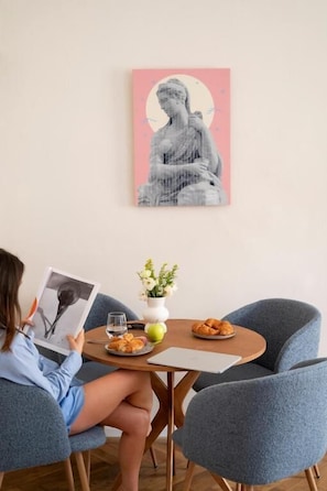 A person reading a book at a table with a Buddha statue, flowers, and food. - Miki Stays - 200m zum Prater (Vienna)