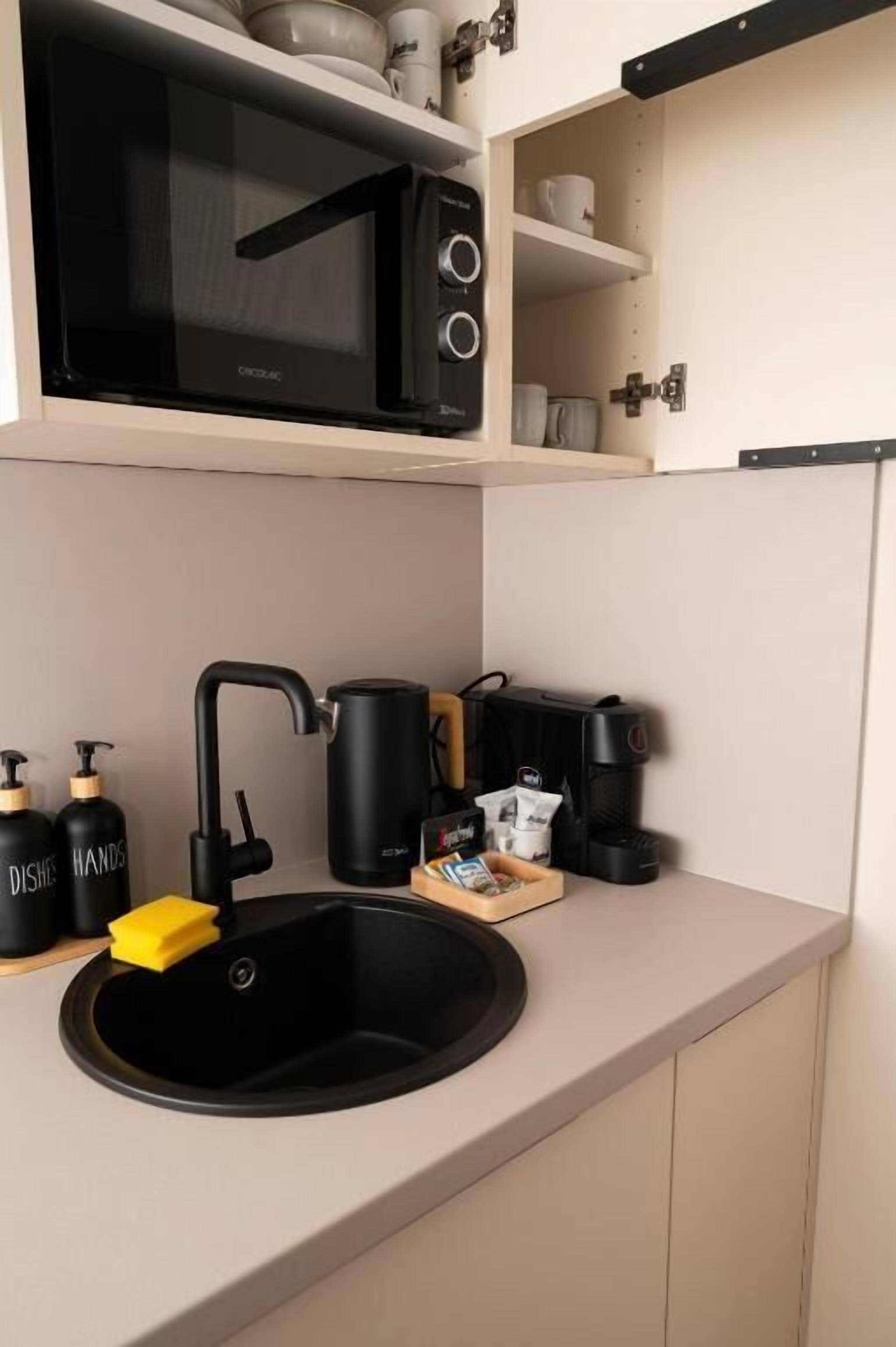 Eine Küche mit einem schwarzen Spülbecken, einer Mikrowelle und einer Kaffeemaschine.
