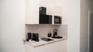 A compact kitchenette with a microwave, coffee maker, and a small countertop.