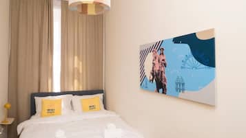 Ein Hotelzimmer mit einem Bett, einem Wandbild und einem Fenster mit Vorhängen.