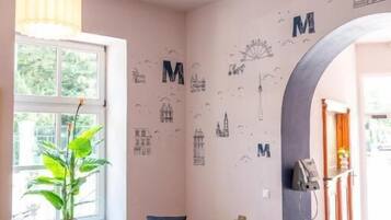Ein Zimmer mit Fenster, einer Pflanze, einem runden Tisch und einer Couch.