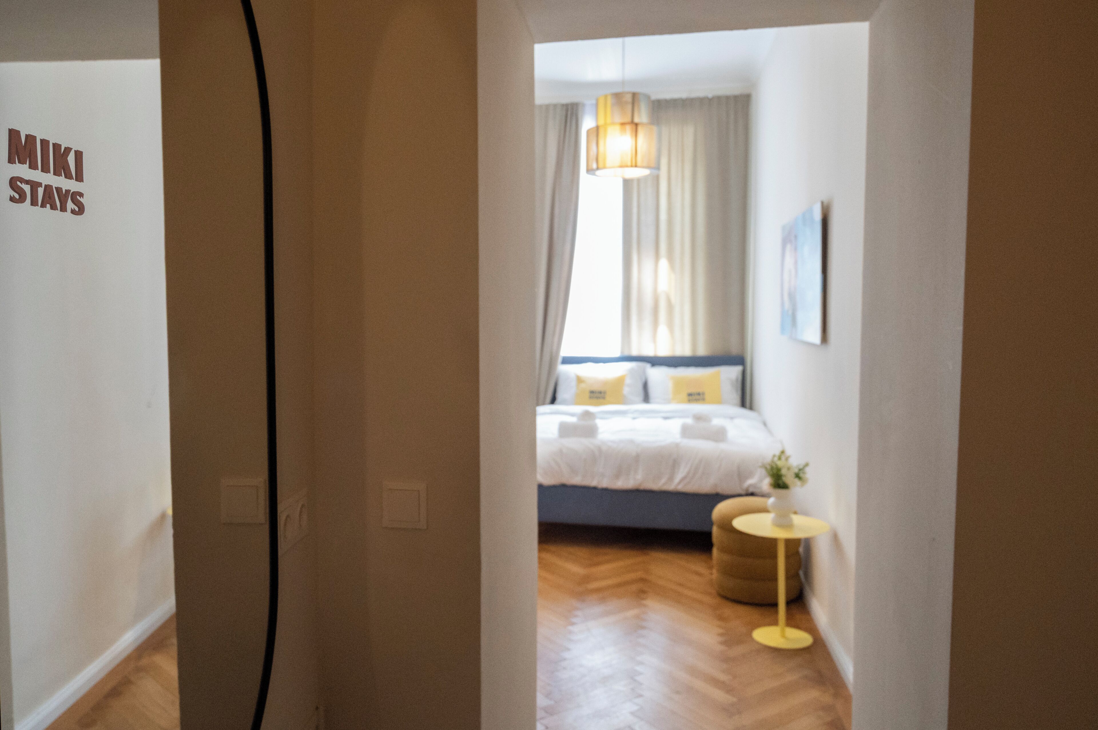 Ein Hotelzimmer mit Bett, Nachttisch, Lampe und einem Fenster mit Vorhängen.