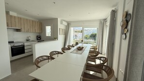 A modern kitchen with a dining area, a coffee machine, and a view of buildings through the window. - Nerja Paradise Rentals - Villa La Marea (Nerja)