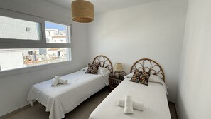 A bedroom with two beds, a window, and a view of buildings outside. - Nerja Paradise Rentals - Villa La Marea (Nerja)