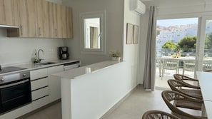 A modern kitchen with a built-in oven, a coffee maker, and a view of a balcony with outdoor seating. - Nerja Paradise Rentals - Villa La Marea (Nerja)