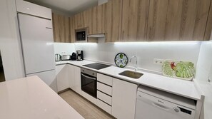 A modern kitchen with white cabinetry, a built-in oven, a dishwasher, and a coffee maker. - Nerja Paradise Rentals - Villa La Marea (Nerja)