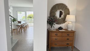 A modern interior with a dining area, a wooden dresser with drawers, a mirror, and a lamp. - Nerja Paradise Rentals - Villa Barranco (Nerja)