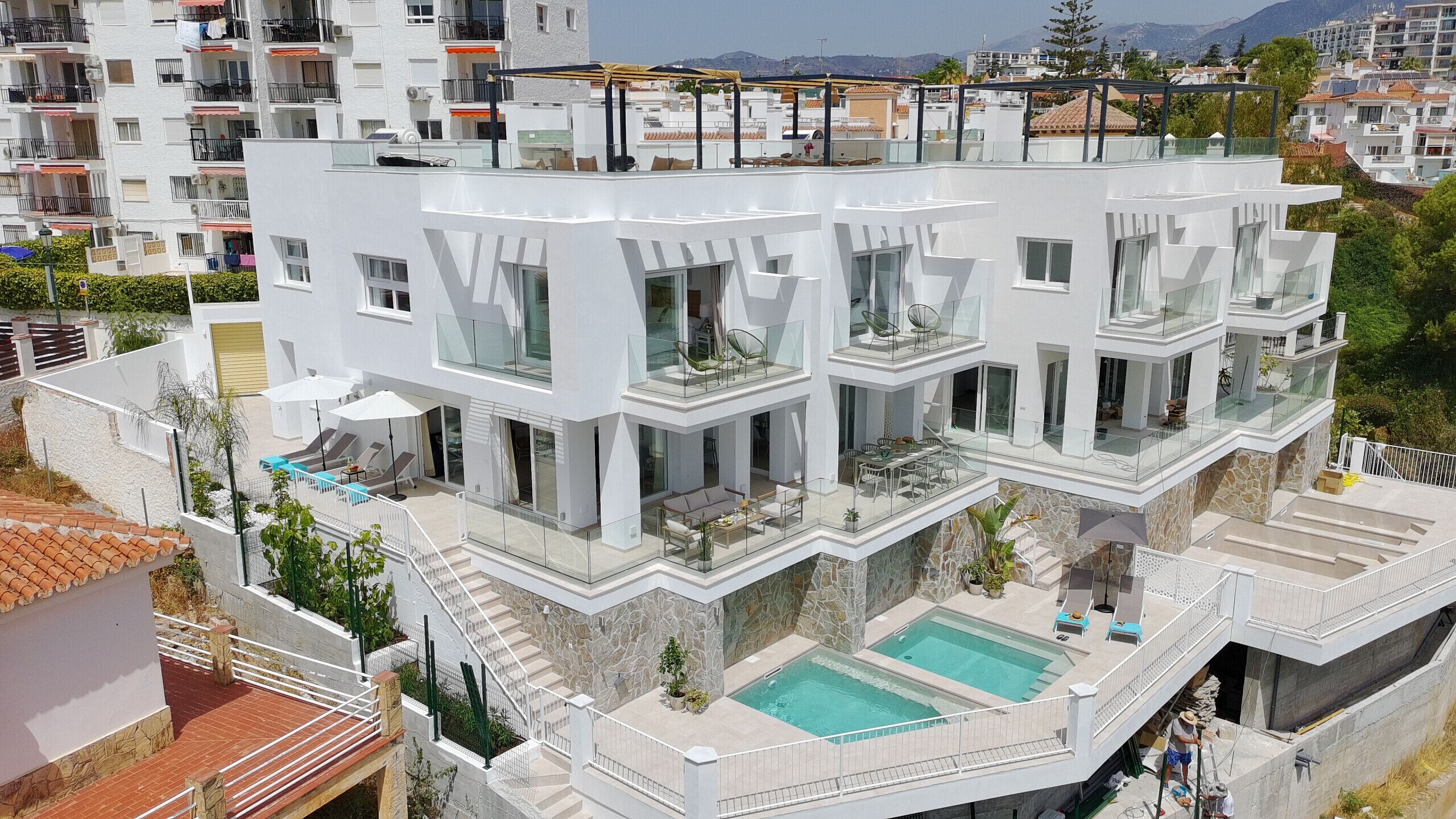 A multi-story residential building with a swimming pool, balconies, and a stone facade.