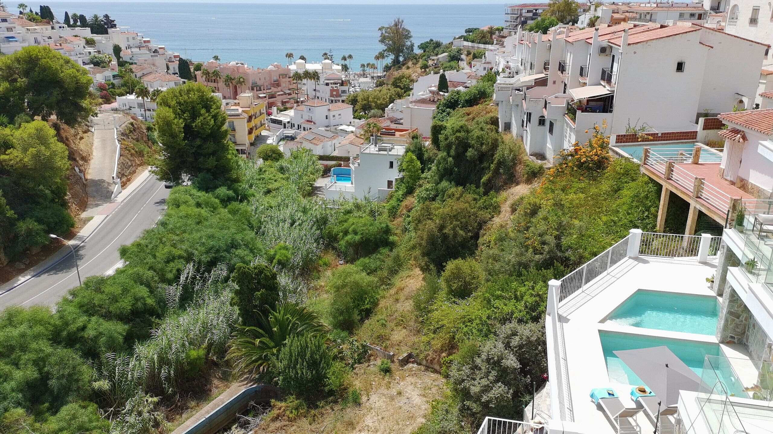 Un quartier résidentiel avec une rue, des espaces verts et une piscine située sur le toit d’un immeuble.