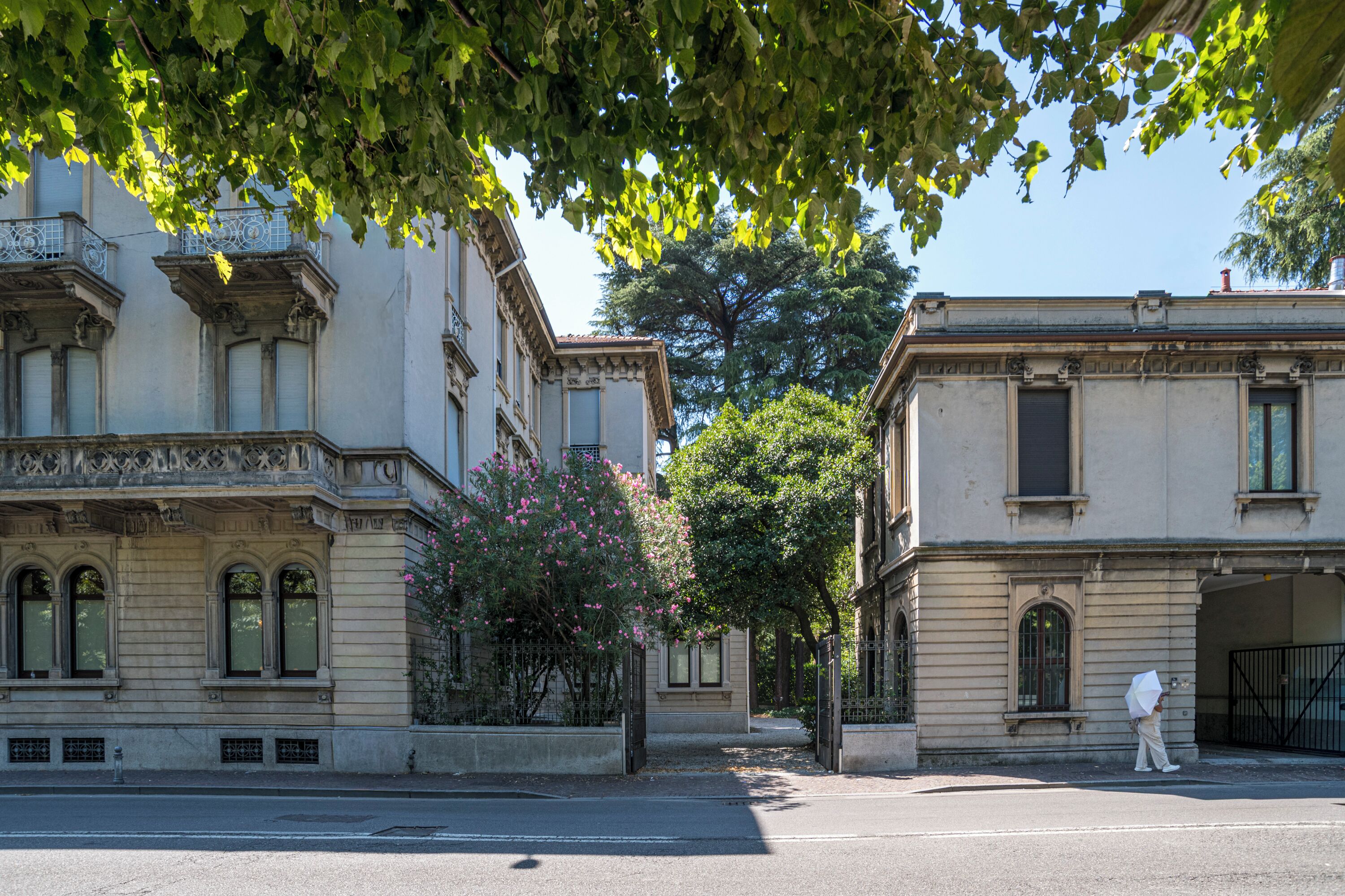 A street view with two buildings, one with a balcony and the other with a gated entrance.