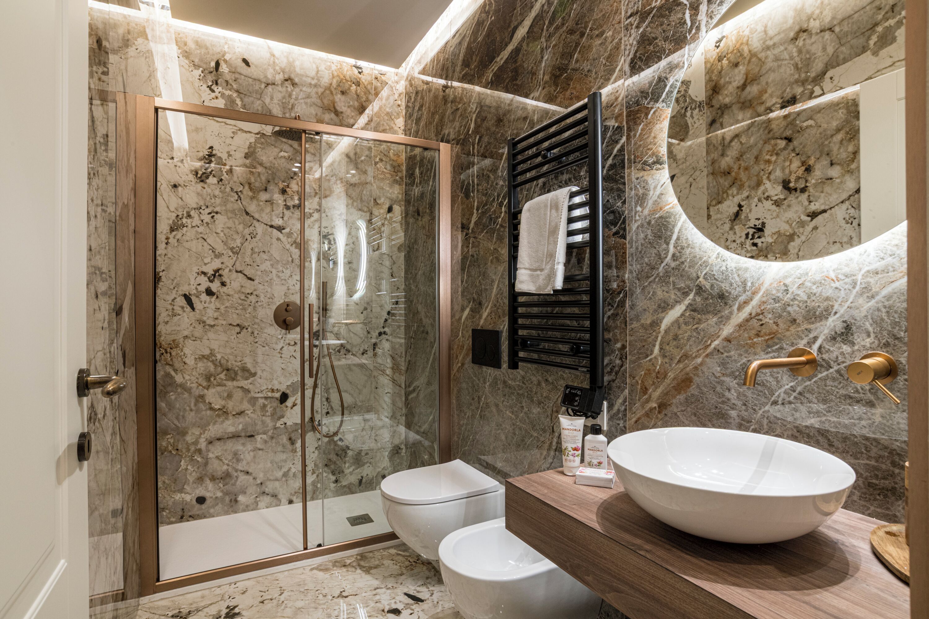 A bathroom with a glass-enclosed shower, a white toilet, and a large white sink with a wooden countertop.