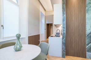A compact kitchen with a built-in stove, a small dining area with a round table and chairs, and a decorative vase on the table.
