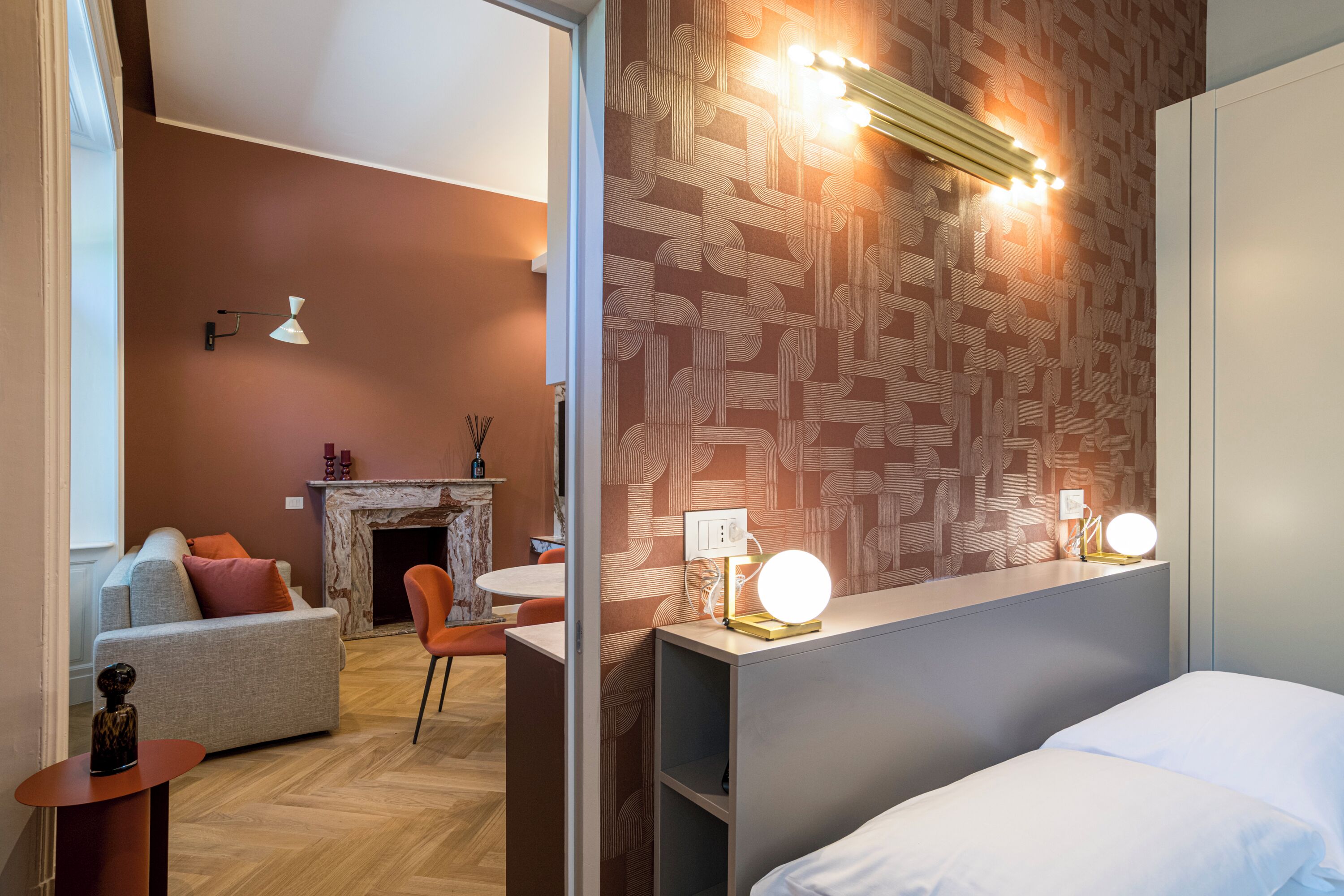 Una moderna camera d'albergo con un letto, una zona salotto con divano e poltrone, un camino e una parete decorata.