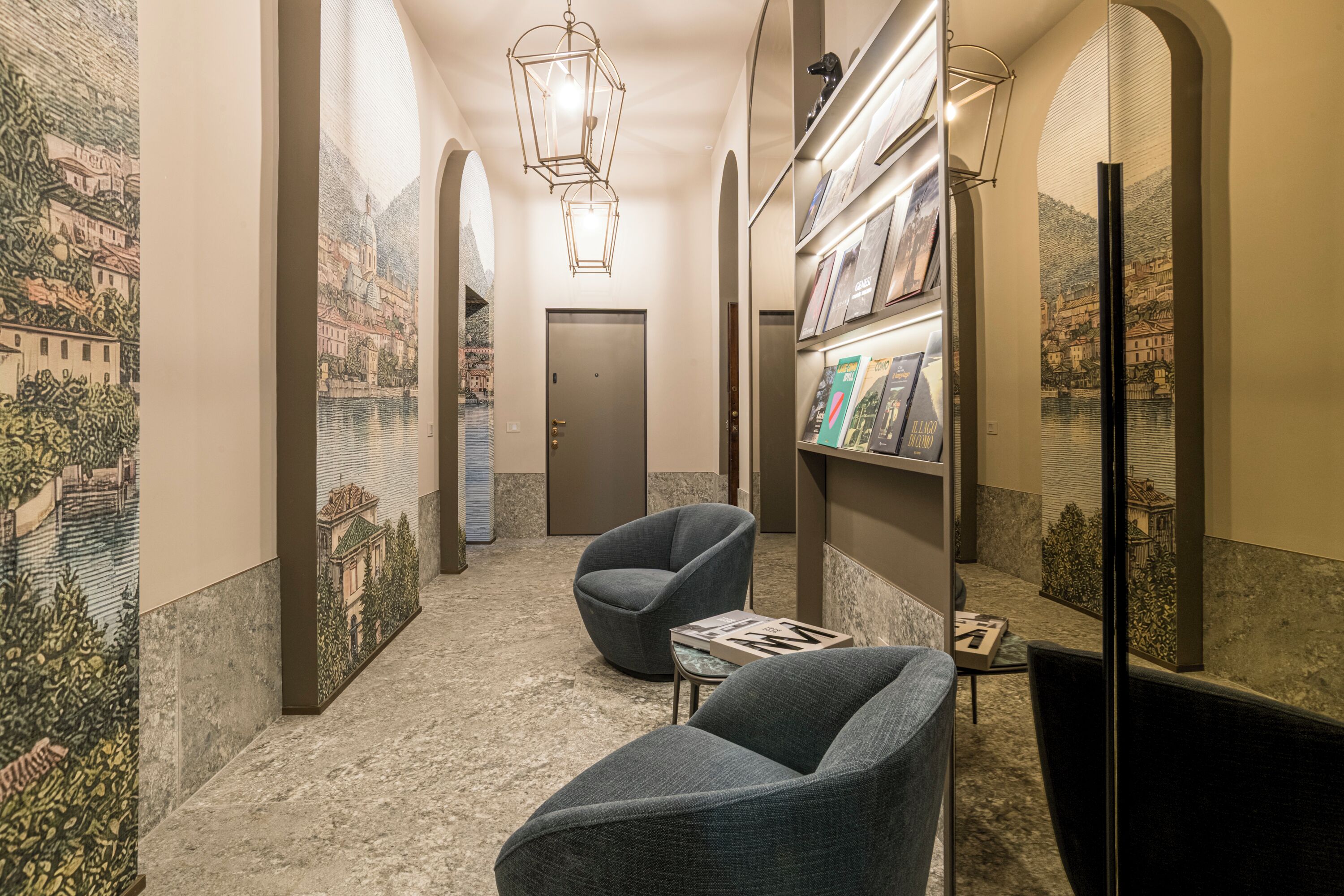 A hallway with a mural, a bookshelf, a chair, and a floor lamp.