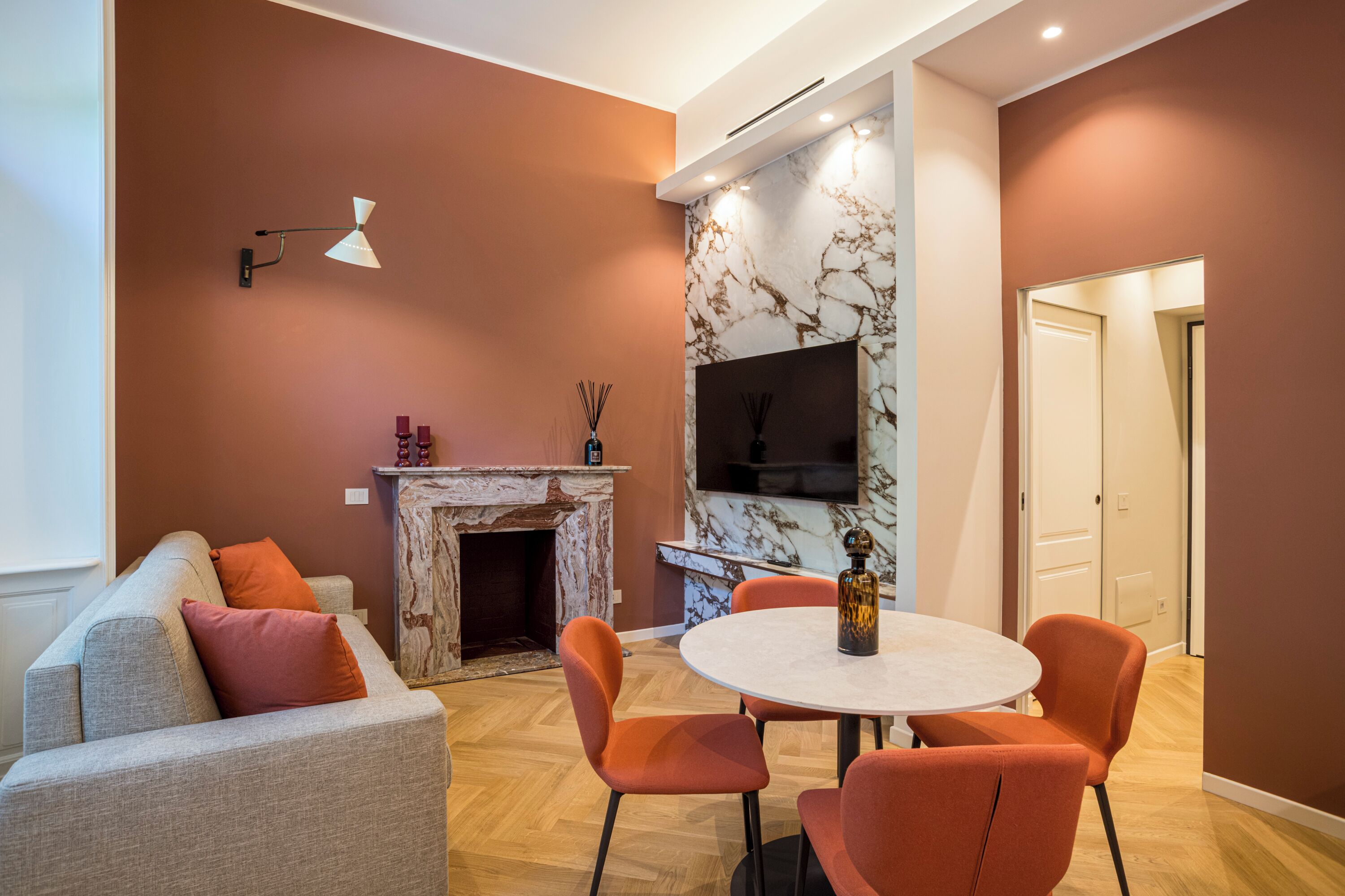 Ein modernes Wohnzimmer mit Kamin, einem runden Esstisch und orangefarbenen Sesseln.