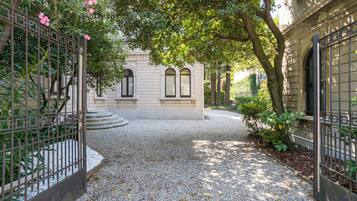A gravel pathway leading to a building with arched windows and a gated entrance.