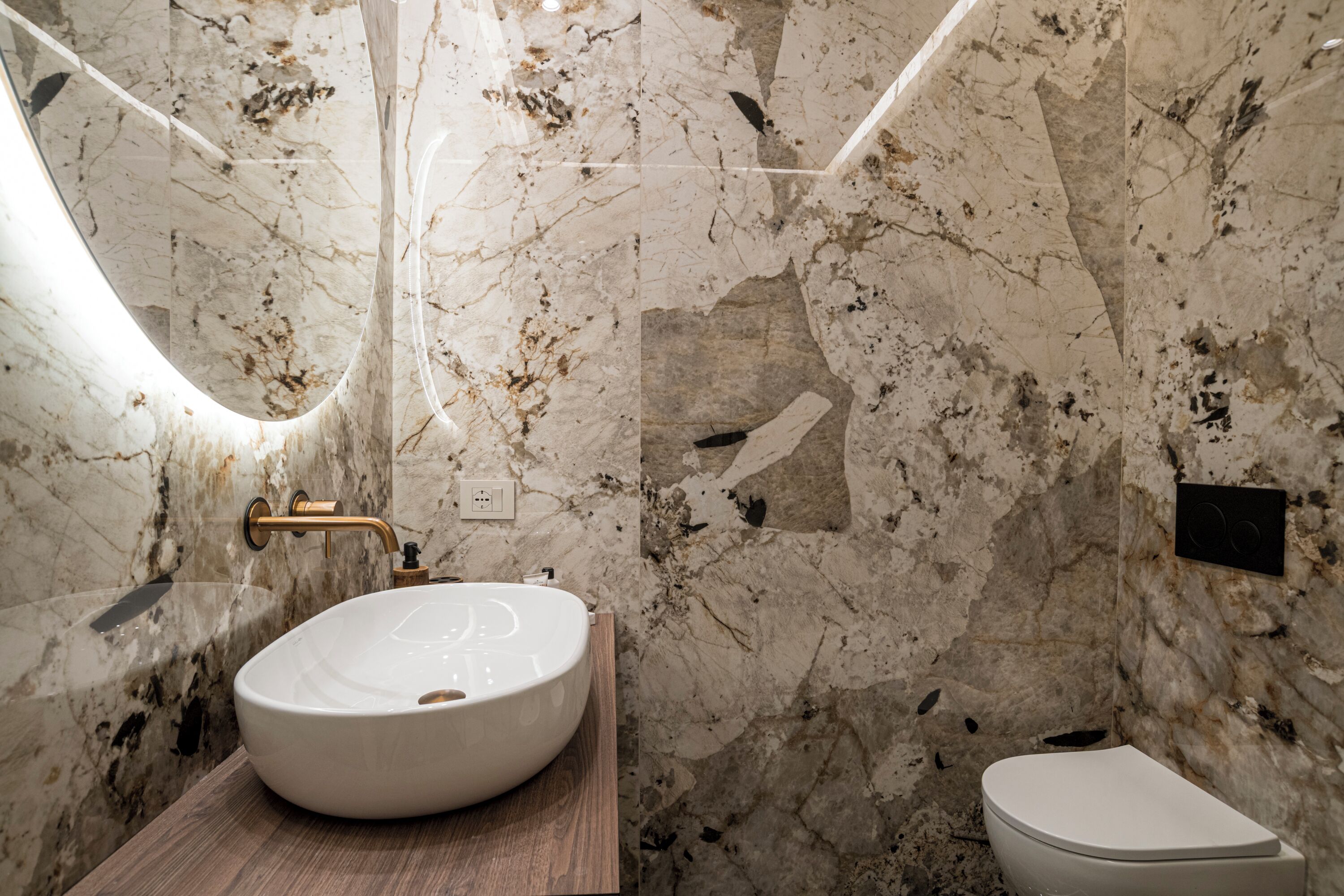 Ein Badezimmer mit Marmorwaschbecken, einem Holzwaschtisch und einer Toilette.