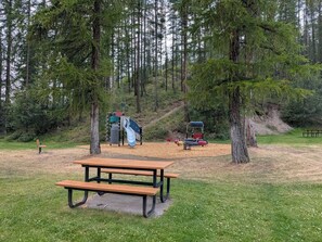 A picnic table in a park with playground equipment and trees in the background. - Spacious Kimberley Mountain Retreat | 5 Bedrooms (Kimberley)