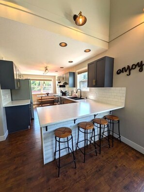 A kitchen with a large island, bar stools, and a wall-mounted sign. - Spacious Kimberley Mountain Retreat | 5 Bedrooms (Kimberley)