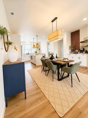 Una cocina moderna con armarios blancos, una mesa de comedor de madera y un detalle azul.